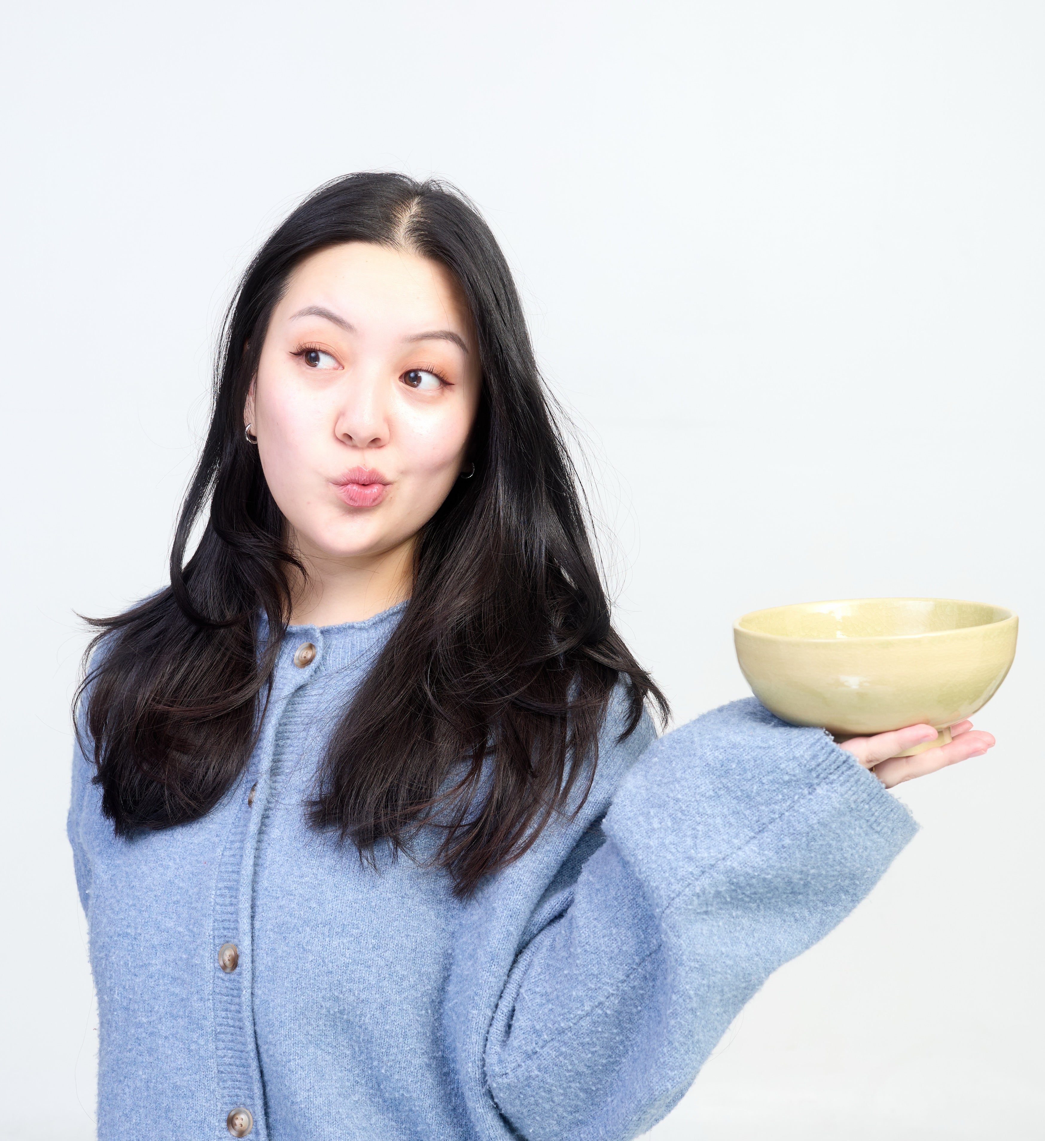 Woman holding a ceramic bowl against a plain background
