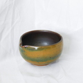 Ceramic bowl with brown and green glaze on a white background
