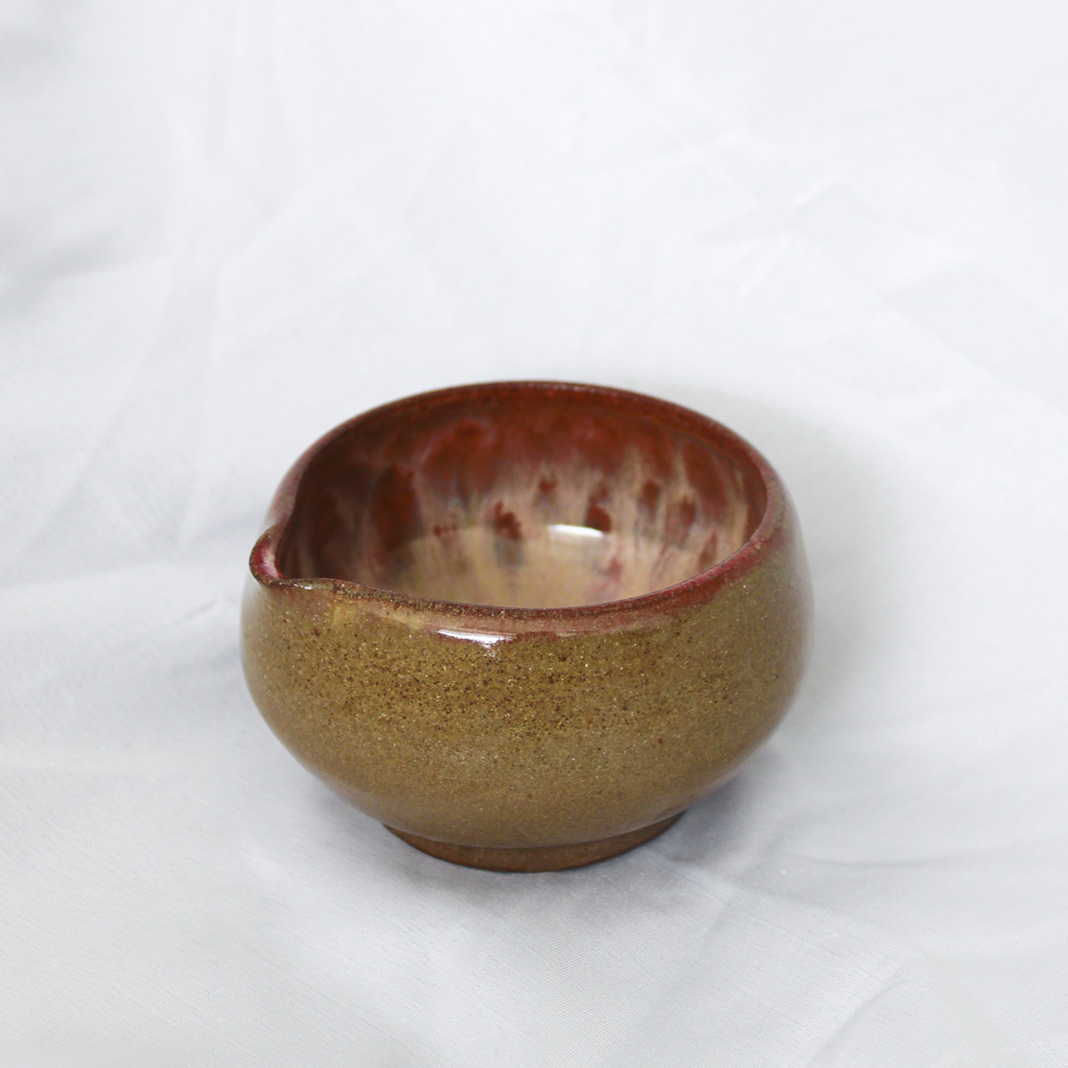 Ceramic bowl with a speckled brown and red design on a white background